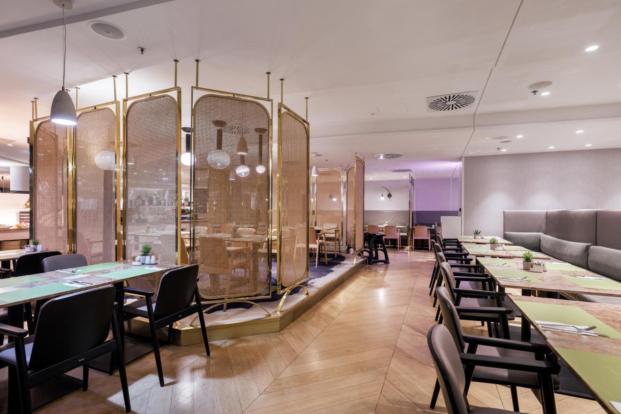 Radisson Blu Resort Swinoujscie Bagian luar foto The photo depicts a modern restaurant interior. It features a layout with several tables and chairs arranged in an organized manner. There is a decorative partition made of delicate mesh or fabric, providing some privacy between different dining area
