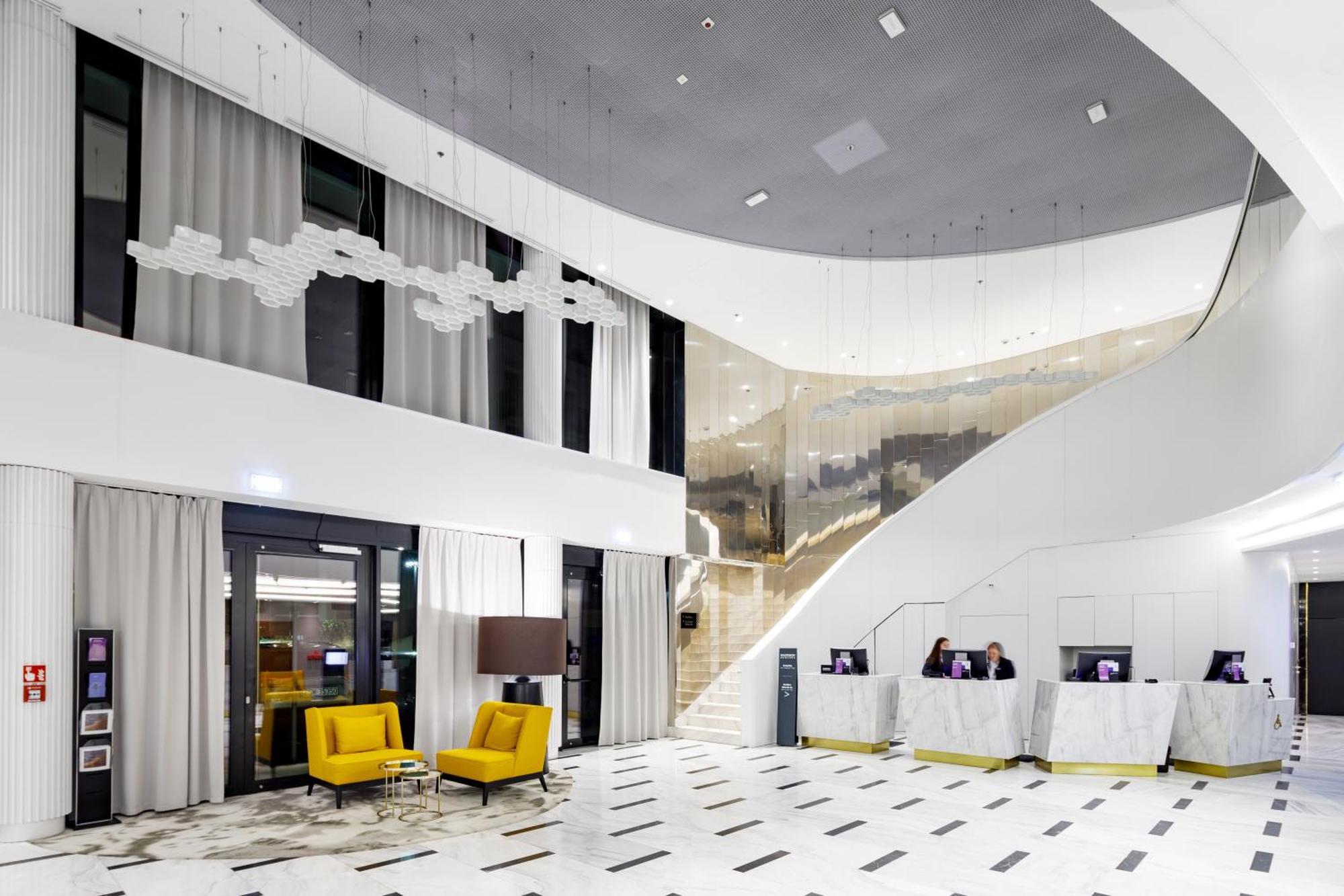 Radisson Blu Resort Swinoujscie Bagian luar foto The photo shows a modern interior space, likely a hotel or a lobby area. It features a spacious, open design with high ceilings and a stylish staircase that leads to an upper level. The walls are mostly white, with large windows allowing natural ligh