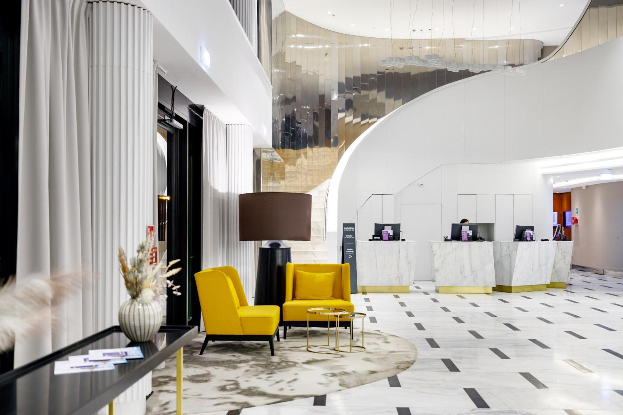 Radisson Blu Resort Swinoujscie Bagian luar foto The photo shows the interior of a modern hotel lobby. The space features a stylish design with a combination of yellow and neutral-colored seating, including two yellow armchairs and a small table. In the background, there is a reception area with ma