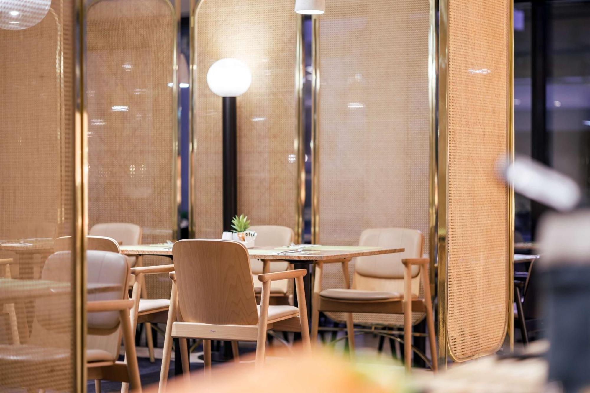Radisson Blu Resort Swinoujscie Bagian luar foto The image shows an interior space, likely part of a restaurant or café. There are several wooden chairs arranged around tables, and the overall decor features soft lighting and warm colors. The walls appear to be partially covered with a woven materi