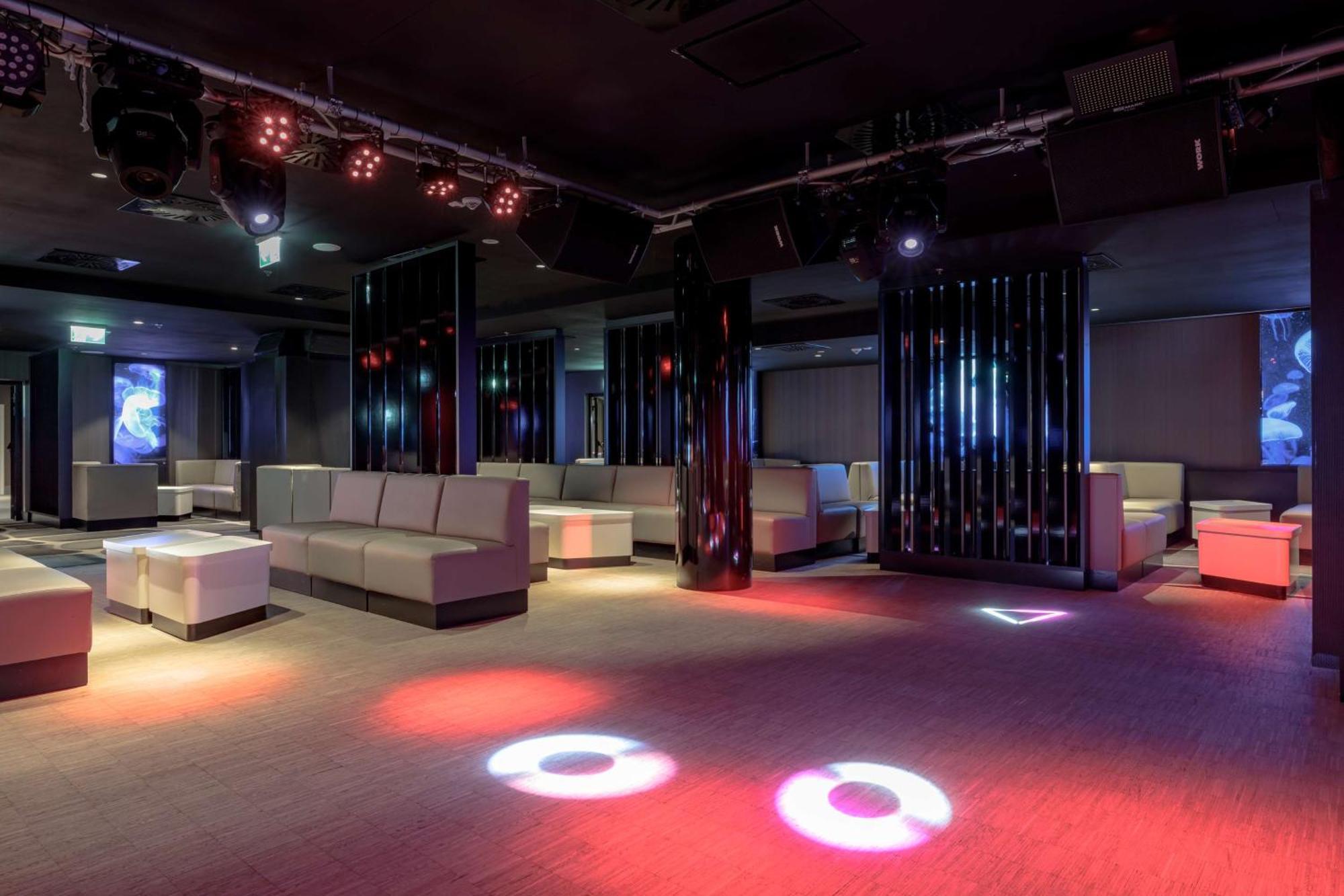 Radisson Blu Resort Swinoujscie Bagian luar foto The photo depicts a modern nightclub interior, featuring a spacious layout with sleek, minimalist seating arrangements. The room has plush seating along the walls, and the floor is illuminated with circular lights in varying colors, creating a vibran