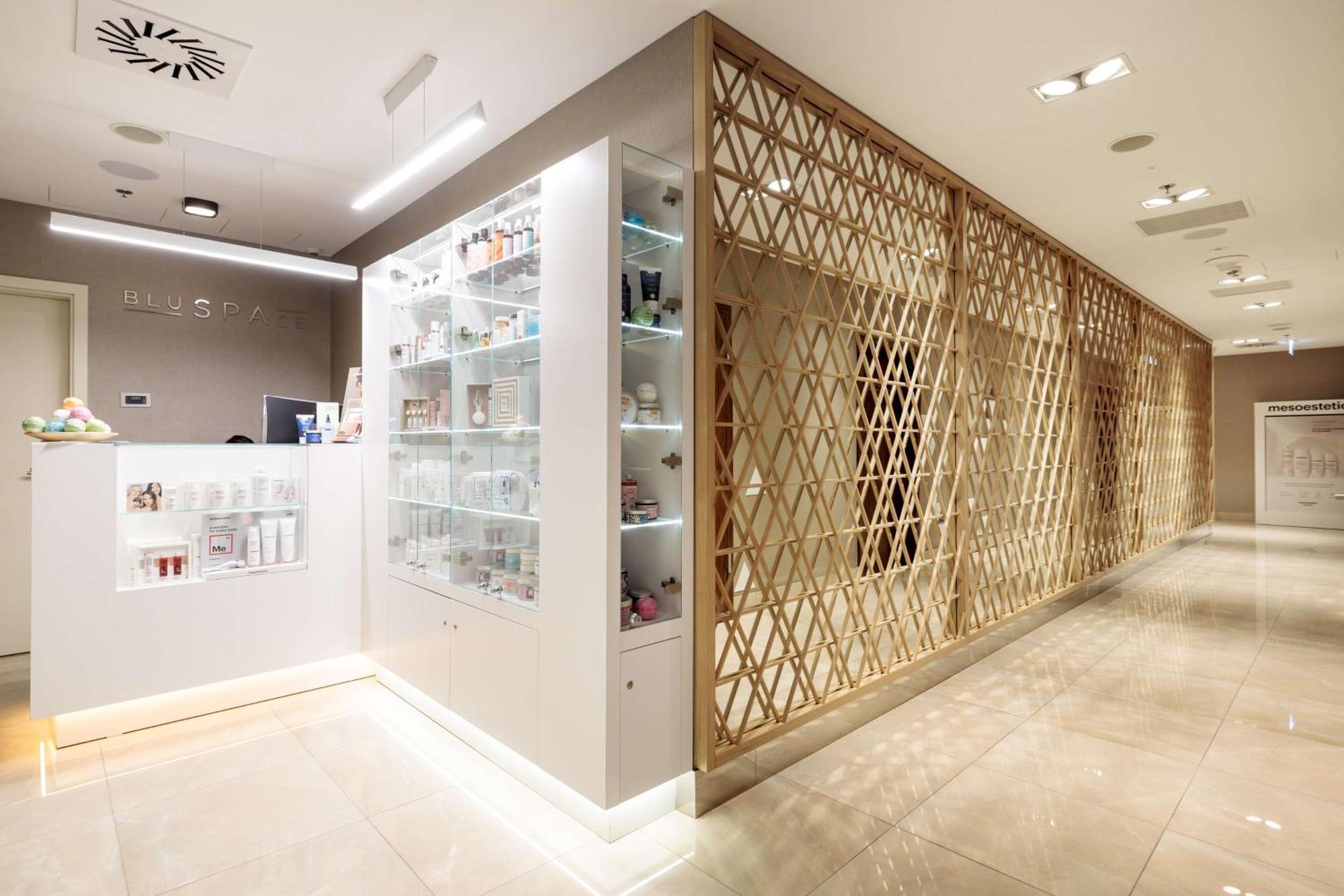 Radisson Blu Resort Swinoujscie Bagian luar foto The photo shows a modern interior, likely from a spa or skincare clinic. On the left, there is a reception area with a sleek white counter and an illuminated display showcasing various skincare products. The wall behind the reception features a glass