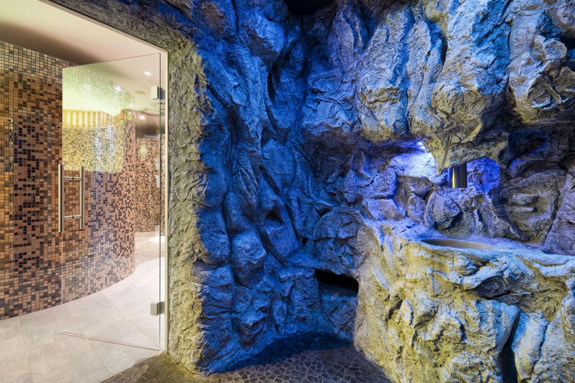 Radisson Blu Resort Swinoujscie Bagian luar foto The photo shows a spa-like environment with a cave-like design. The walls are styled to resemble natural rock formations, featuring textures and colors that suggest a stone surface. Soft blue lighting highlights the contours of the rocks, creating a 